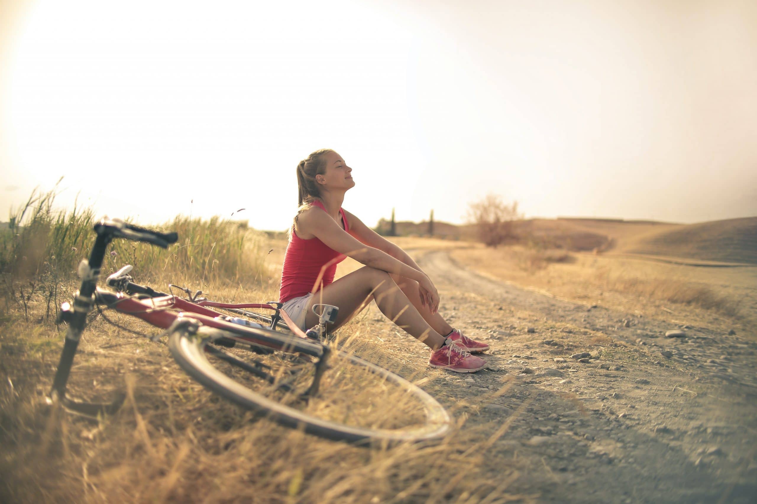 sportive-woman-with-bicycle-resting-on-countryside-road-in-3771836